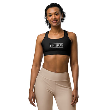 Female model wearing A HUMAN™ black sports bra with signature white logo.
